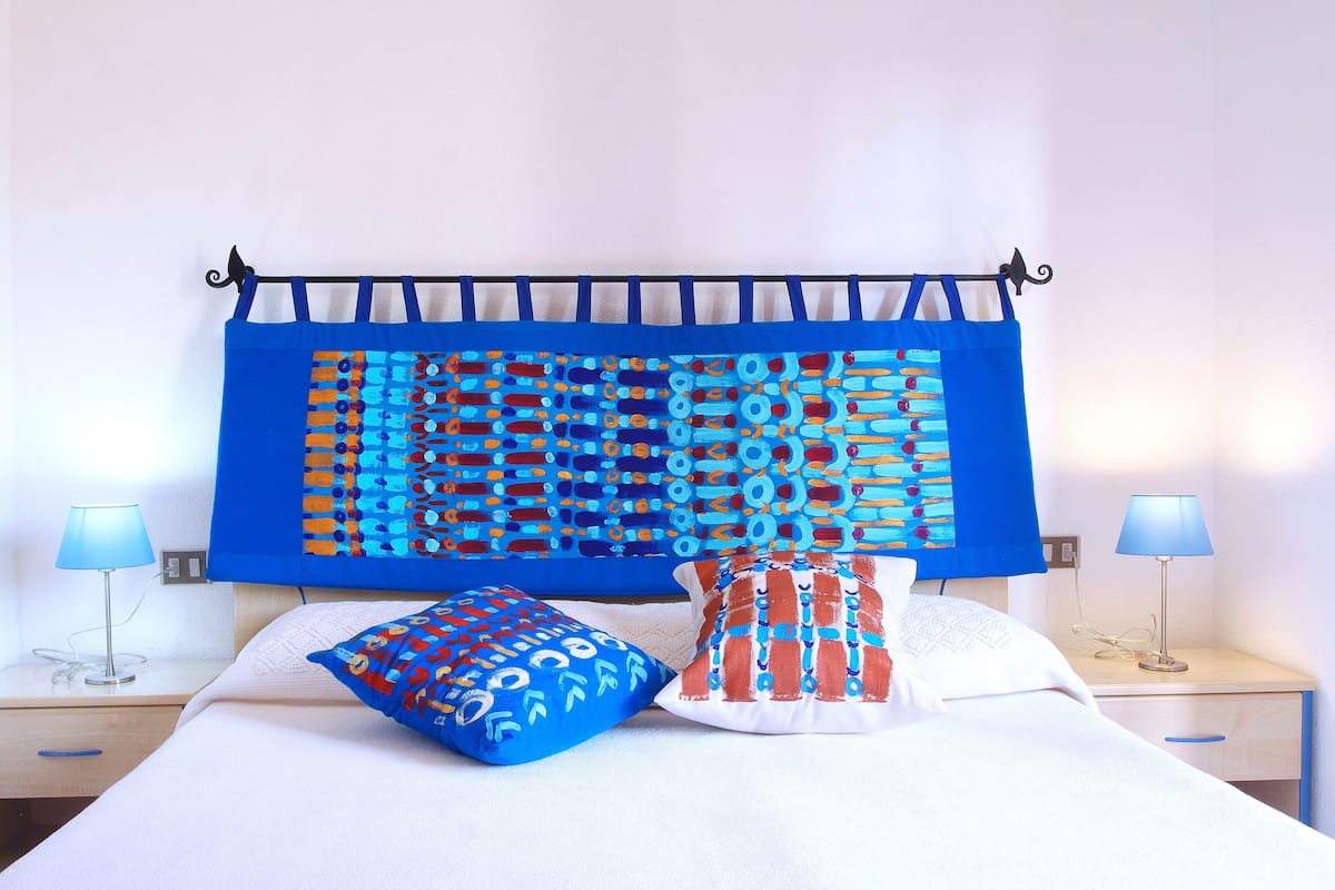 A bed with a blue and orange patterned headboard, two pillows, and bedside lamps.