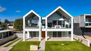 A modern two-story house with large glass windows, a flat roof, and a well-maintained lawn. - Magic Beach Robe - Luxury Beachfront Escape (Robe)