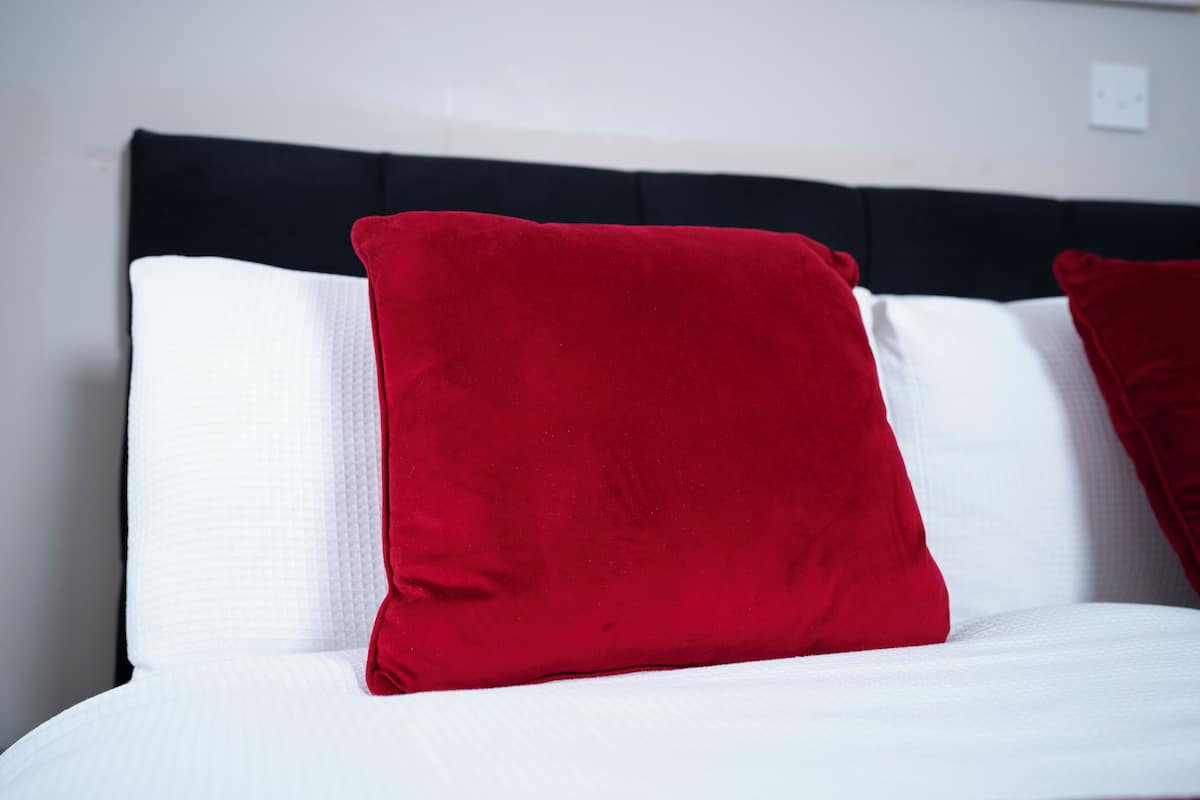A bed with white and red pillows and a black headboard.