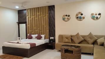 A modern hotel room with a large bed, a sofa, a small table, and decorative wall art.