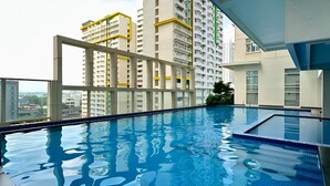 A rooftop swimming pool with a clear view of high-rise buildings in the background. - Charming, Comfy and Stylish Condo Stay! (Makati City)