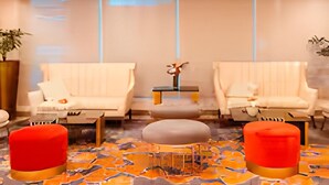 A modern hotel lobby with two sofas, a coffee table, and red ottomans. - Charming, Comfy and Stylish Condo Stay! (Makati City)