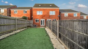 A residential area with brick houses, a wooden fence, and a small lawn. - Four-bedroom home with garden, workspace and easy city access (West Midlands)