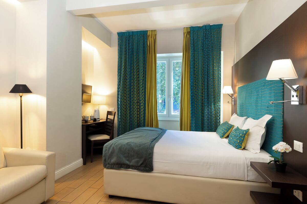 A modern hotel room with a large bed, a desk, and a chair.