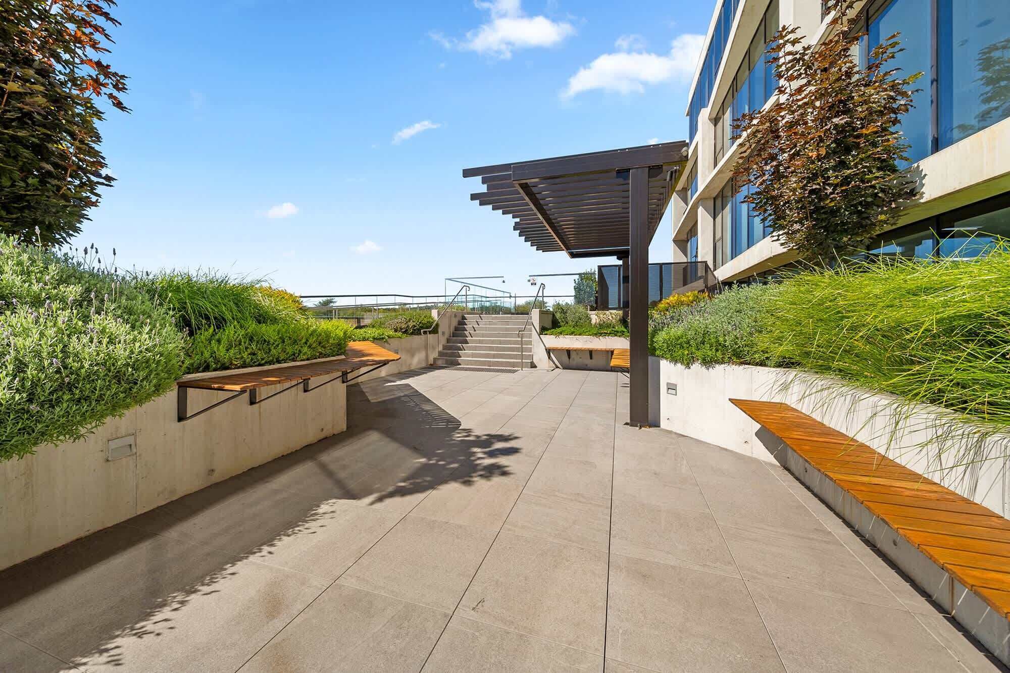 A modern outdoor pathway leading to a building with a covered staircase.