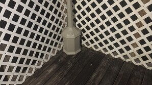 A wooden deck with a lattice fence and a single metal pole.
