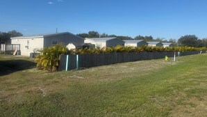 A row of single-story mobile homes with a wooden fence and a yellow fire hydrant in the foreground.