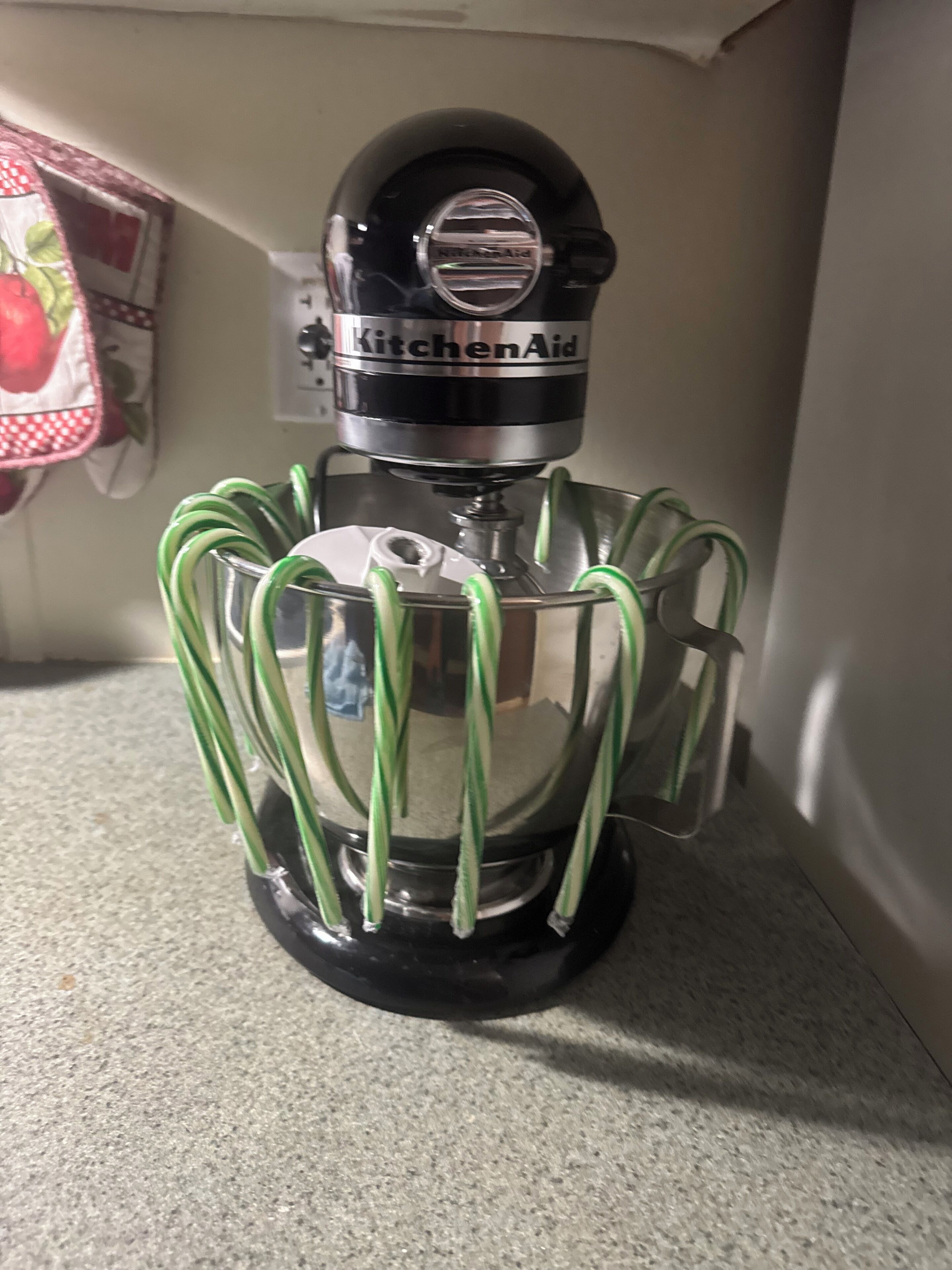 A KitchenAid stand mixer with a clear mixing bowl and green beaters.