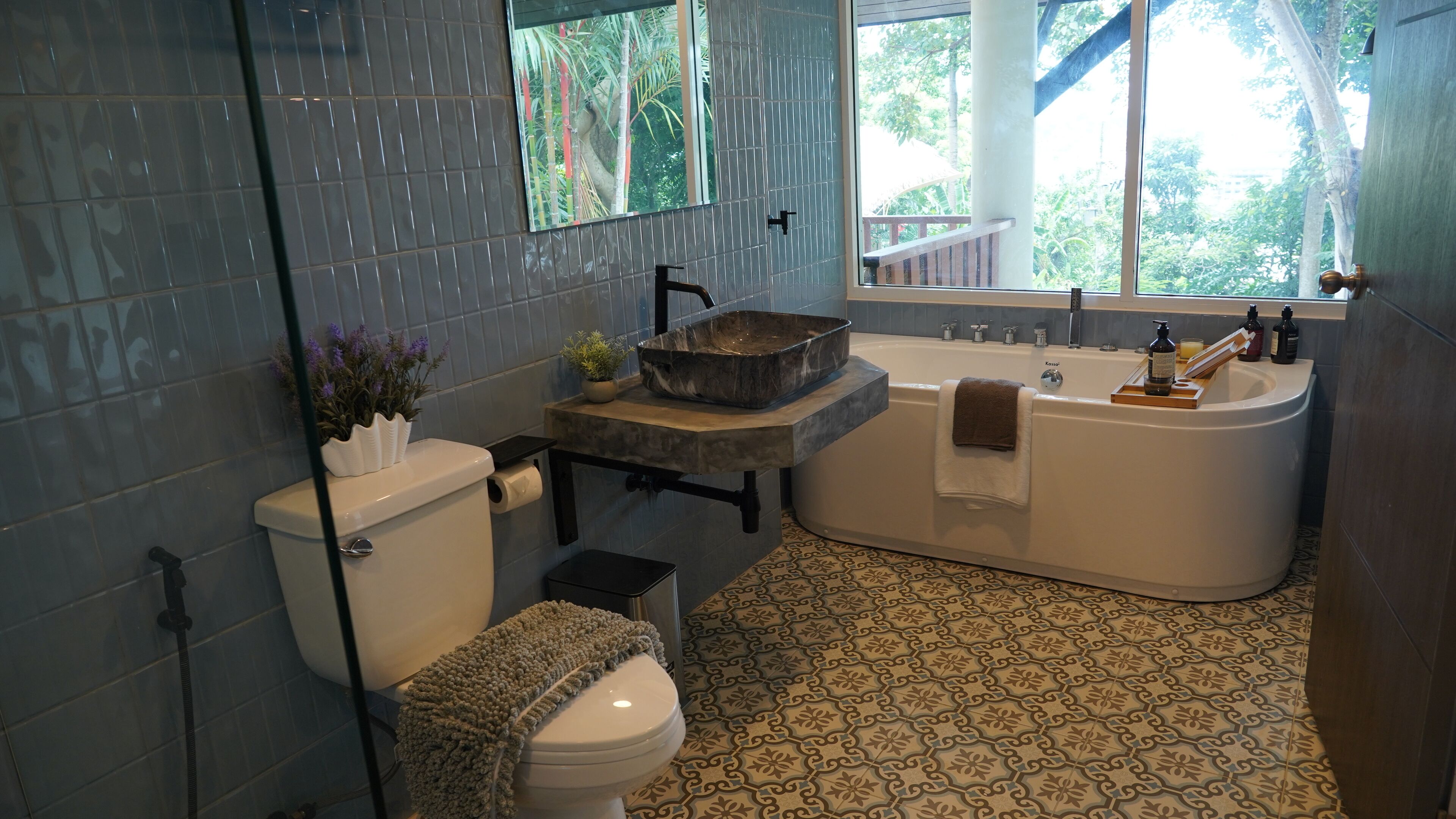A bathroom with a marble sink, bathtub, and patterned floor tiles.