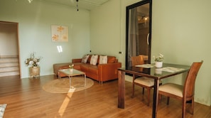 A living room with a sofa, coffee table, dining table, chairs, and a large window. - Jaokhun Hilltop Patong Phuket (Patong)