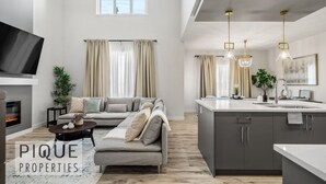 Ein modernes Wohnzimmer mit grauem Sofa, einem Flachbildfernseher und einem Kamin.