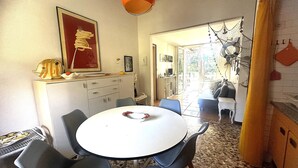 A dining area with a round table and chairs, a kitchen area with cabinets, and a view of the outdoors. - VILLA DUNE NORTH SD4 - TYPE B2 4+0 - B00043 (Bibione Pineda)
