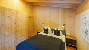 Een kamer met houten lambrisering, een bed, bedlampen en een wandlamp.