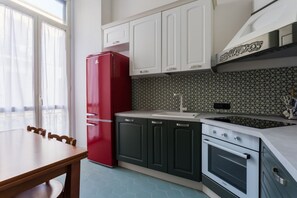 A kitchen with white cabinets, a red refrigerator, a sink, and an oven. - Nea Family in Naples city centre (Napoli)