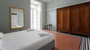 Una habitación de hotel con cama, un espejo grande, un armario y una mesita.
