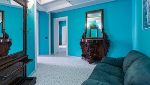 Una habitación con paredes color turquesa, un aparador de madera, un espejo y un sofá verde.
