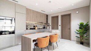 A modern kitchen with a marble countertop, wooden cabinets, and a built-in oven. - Spacious 1BR with Modern Amenities in Westwood Grande, JVC (Jumeirah Village Circle)