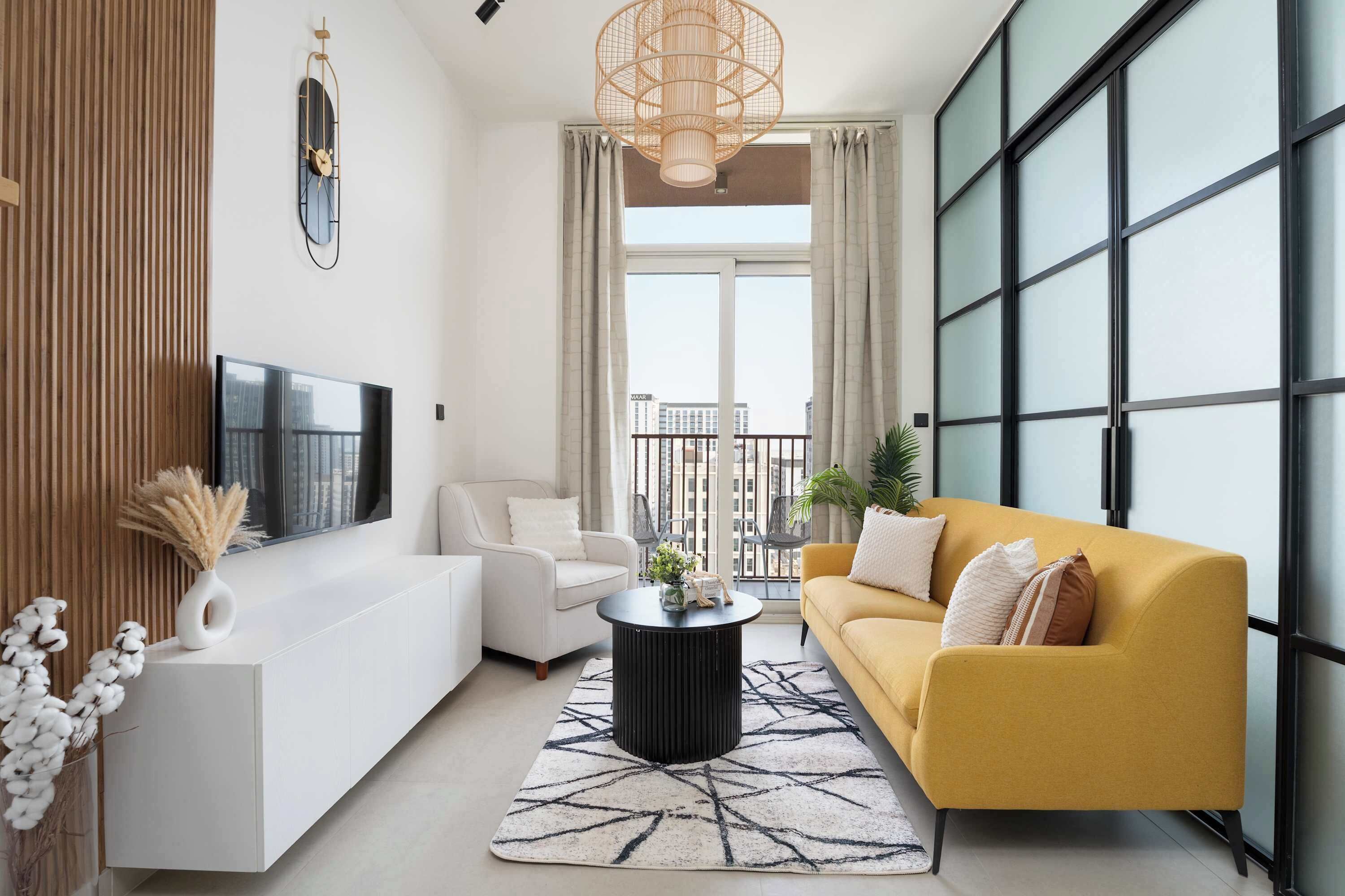 Un salon moderne avec un canapé blanc, un canapé jaune, une table basse noire et une grande fenêtre avec des rideaux.