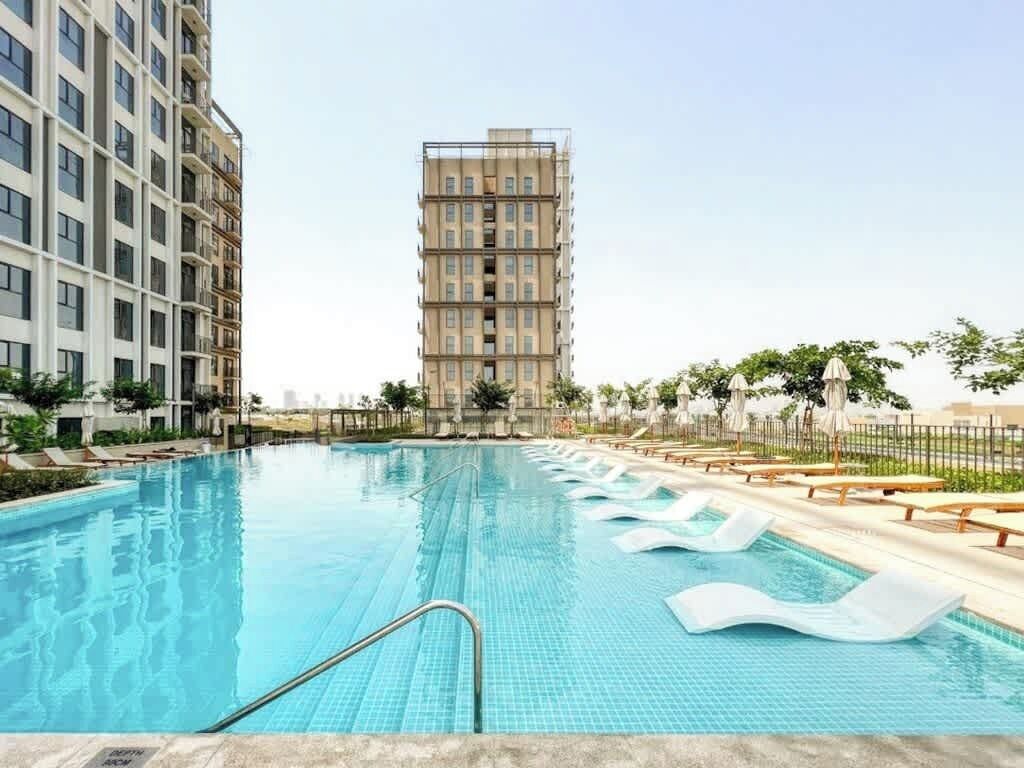 A swimming pool with lounge chairs and a tall building in the background.
