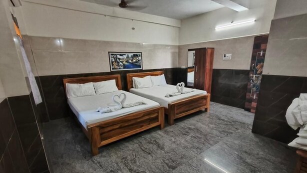 A hotel room with two beds, a ceiling fan, and a painting on the wall. - VRS INN (Walajapet)
