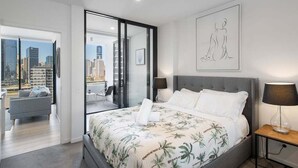 A modern bedroom with a large bed, a city view through a glass door, and a minimalist decor. - Top Location Convenient City View Modern Living (Brisbane)