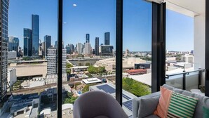 A modern living room with a large window offering a city view. - Top Location Convenient City View Modern Living (Brisbane)
