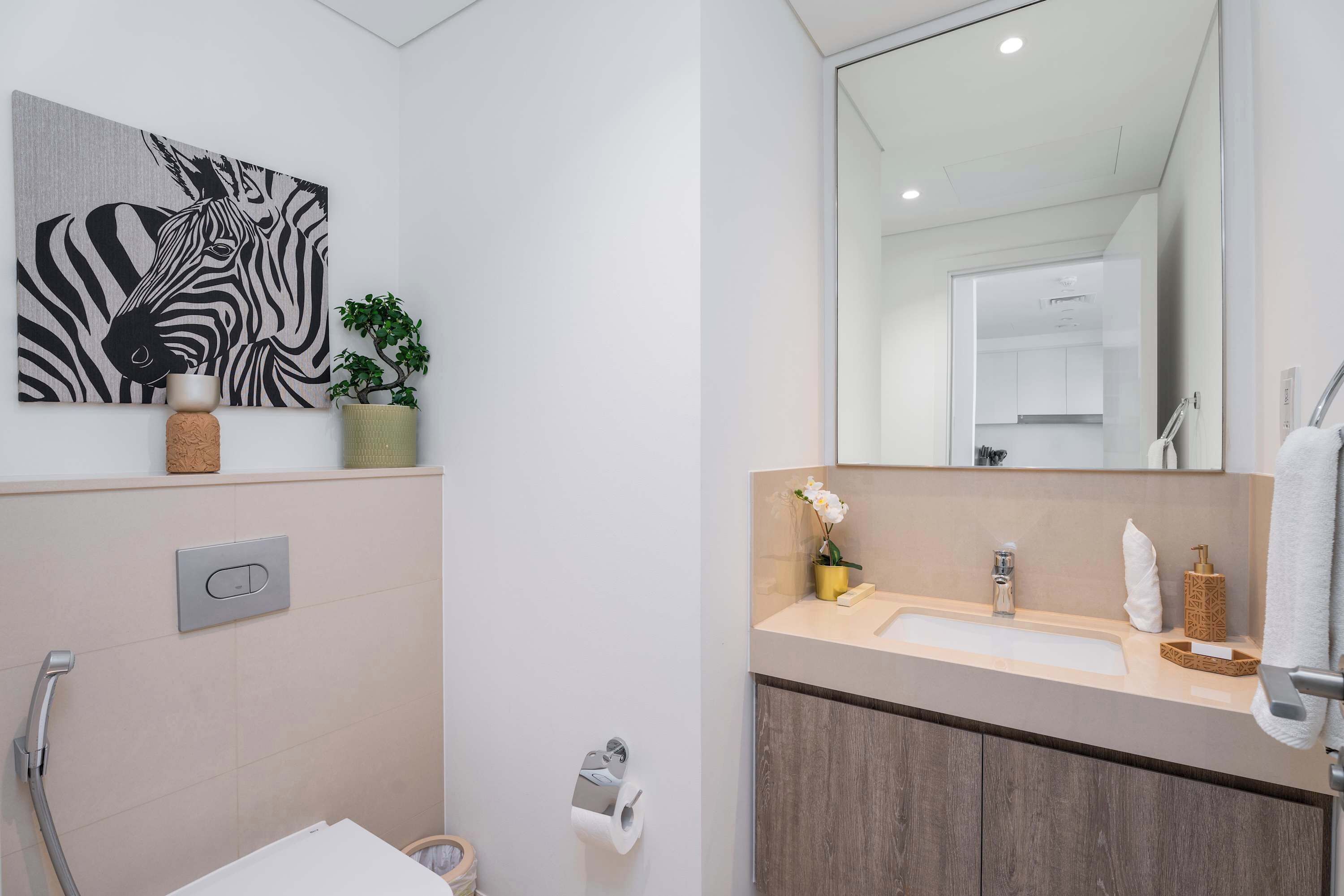 Een moderne badkamer met een kunstwerk met zebra’s, een wastafel met spiegel en een douche.