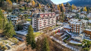 Eine bergige Stadt mit traditioneller Architektur, darunter mehrstöckige Gebäude mit Balkonen und ein zentrales Gebäude mit markantem Dach.