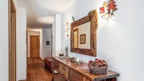 Ein Flur mit Holzboden, einer Holzbank, einer Holzkommode mit Spiegel und Wandleuchten.