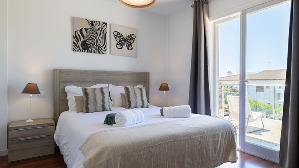 Ett hotellrum med en stor säng, två sänglampor, utsikt över omgivningarna genom en skjutdörr och konstverk på väggen.