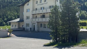 A multi-story building with balconies, labeled "Inntalerhof," set against a mountainous backdrop. - Apart Inntalerhof (Toesens)