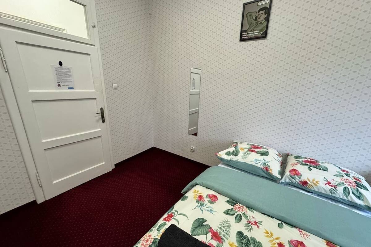 A hotel room with a bed, a door, and a wall-mounted mirror.