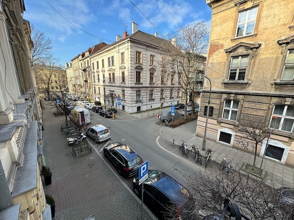 A street view with parked cars, a pedestrian crossing, and buildings with classical architecture. - Fantastic Inn Kraków - GR6 (Krakow)