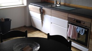 A kitchen with a window, a sink, a stove, and a dining table with a glass serving tray. - 140 sqm, 5 rooms, up to 10 people (Ludwigshafen am Rhein)