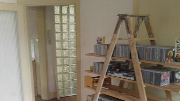 A room with a wooden ladder leaning against a wall, a white bed, and a door leading to another room. - 140 sqm, 5 rooms, up to 10 people (Ludwigshafen am Rhein)