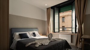 Een hotelkamer met een bed, een raam met gordijnen, een radiator en een bureau met een stoel.
