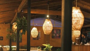 A restaurant interior with wooden tables and hanging wicker lamps.