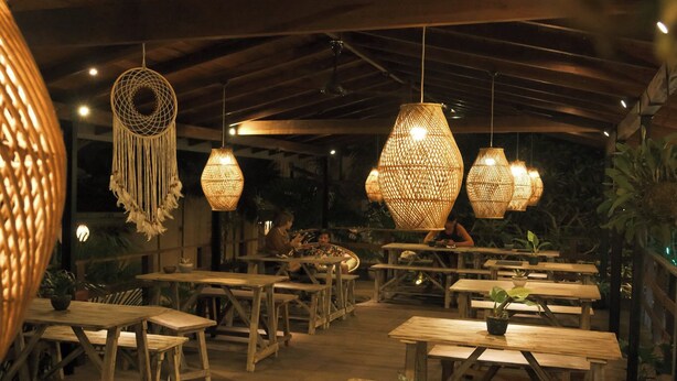 An indoor dining area with wooden tables and hanging wicker lamps.
