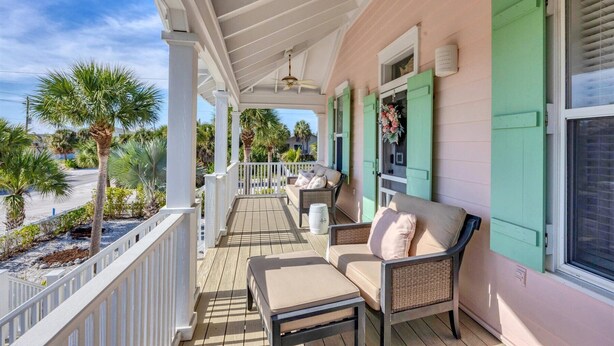A covered porch with a white railing, a cushioned bench, and a wicker chair. - The perfect Beach Cottage getaway! (Placida)