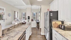 A modern kitchen with white cabinetry, a marble countertop, and a black refrigerator. - The perfect Beach Cottage getaway! (Placida)