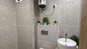 Moderni kylpyhuone, jossa on wc, pesuallas ja seinälle asennettu vedenlämmitin.