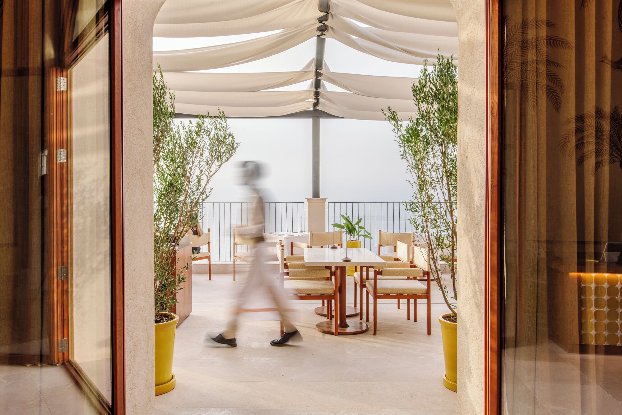 Un espace repas extérieur moderne, avec une table et des chaises, entouré de plantes en pot.