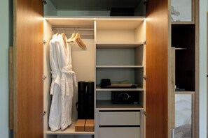 A walk-in closet with wooden doors, shelves, and hanging robes. - Gran Hotel Margalida Mallorca by Annua Signature - New Opening (Banyalbufar)