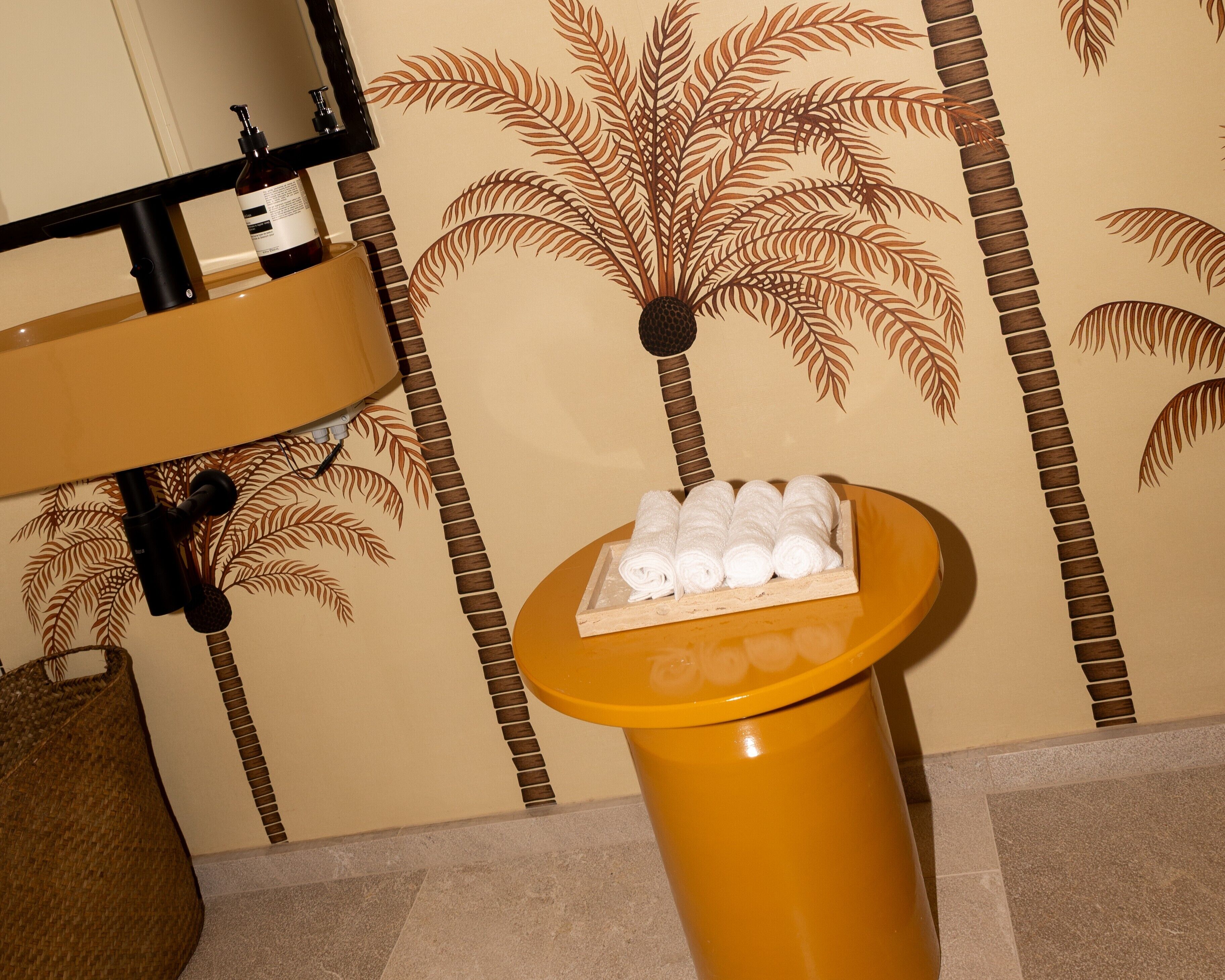 A bathroom with a sink, a towel rack, and a small table with rolled towels.