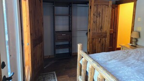 A bedroom with a wooden bed frame, a wardrobe, and a built-in closet with shelves. - Tranquil 1-bedroom apartment in Donnelly perfect for a getaway (Donnelly)