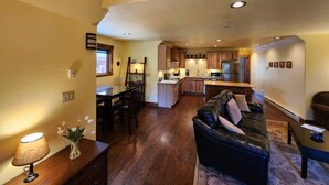 A spacious living area with a dark leather sofa, wooden dining table, and a kitchen in the background. - Tranquil 1-bedroom apartment in Donnelly perfect for a getaway (Donnelly)
