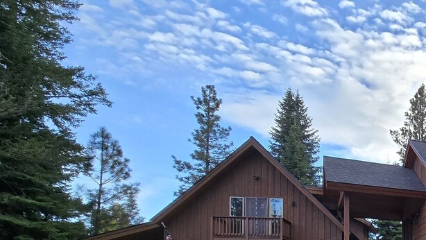 A large wooden house with a garage, a covered porch, and a stone wall. - Tranquil 1-bedroom apartment in Donnelly perfect for a getaway (Donnelly)