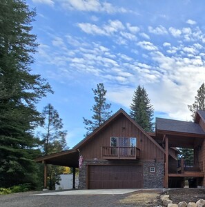 A large wooden house with a garage, a covered porch, and a stone wall.