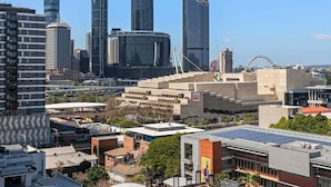 A cityscape with modern skyscrapers, a Ferris wheel, and a mix of commercial and residential buildings. - Central 2BR Gem | Modern Comfort City & River View (Brisbane)