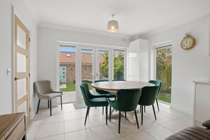 A modern kitchen with white cabinets, a round wooden table, and green chairs. - Beautiful Luxury Beach House 4 bed 4 Bath newly renovated (Gorleston-on-Sea)